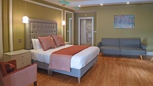 A bedroom with a bed, bedside tables, a chair, a sofa, and a painting on the wall. - Moy Hotel (Foxford)