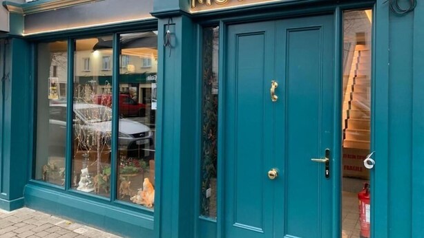 A hotel entrance with a teal facade, double doors, and a visible fire extinguisher inside. - Moy Hotel (Foxford)