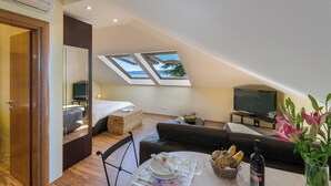 A modern room with a bed, a sofa, a dining table with a vase of flowers, and a TV. - Modern, fully equipped studio in a top location (Crikvenica)