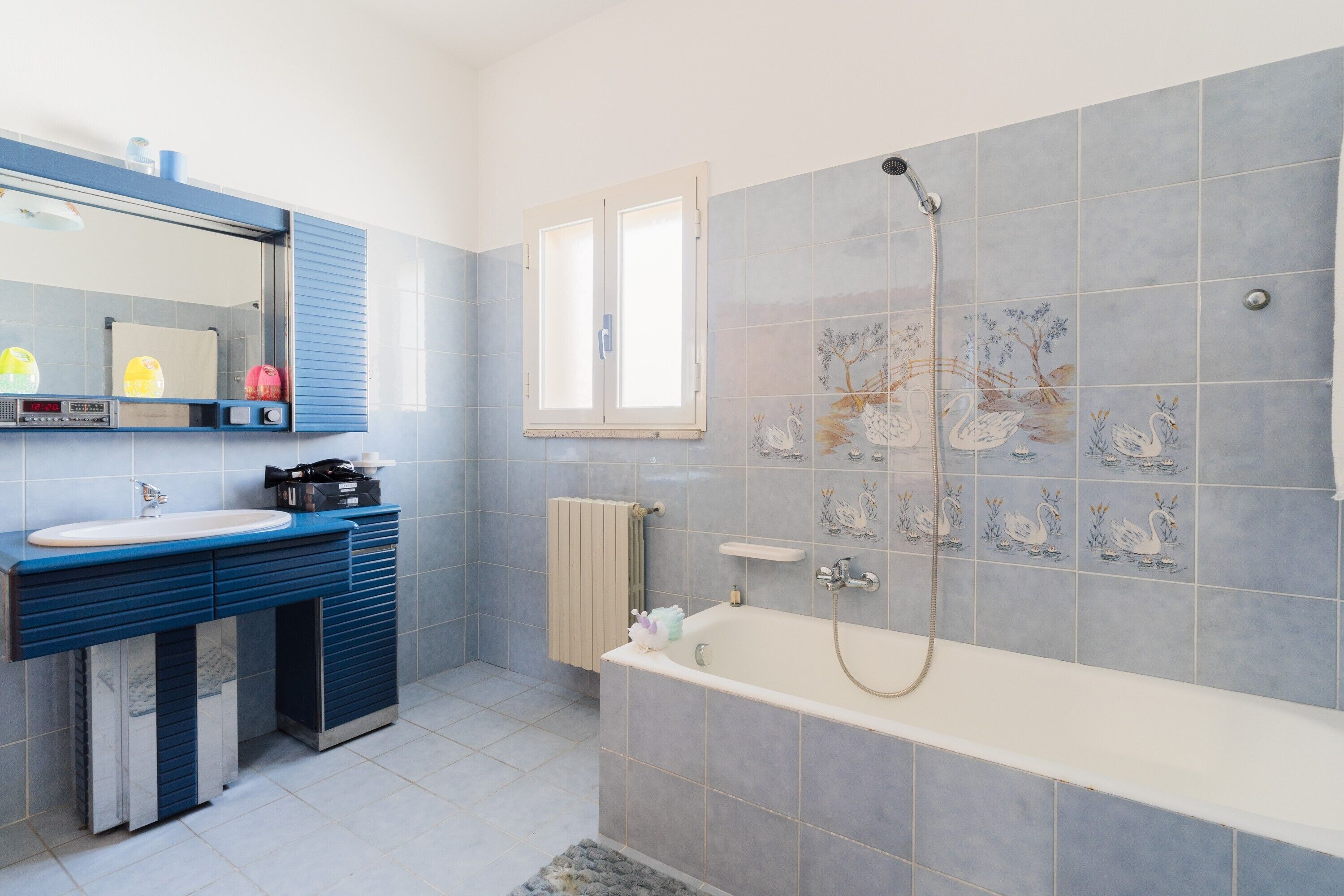 Un baño con bañera, lavamanos, espejo y ventana.