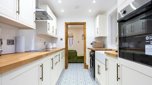 A modern kitchen with white cabinets, a wooden countertop, a washing machine, and a black oven. - Tranquil Stoke-on-trent 4bed, 2 Bath, Parking (Stoke-on-Trent)