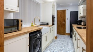 A compact kitchen with a washing machine, a microwave, and a sink. - Tranquil Stoke-on-trent 4bed, 2 Bath, Parking (Stoke-on-Trent)