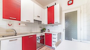 Een moderne keuken met rode en witte kastjes, een spoelbak, een fornuis en een eethoek.