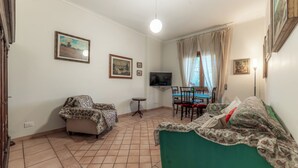 Een woonkamer met een bank, een stoel, een televisie en een bijzettafeltje.