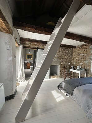 Ein rustikaler Raum mit schräg verlaufender Decke, Steinwand und Kamin.