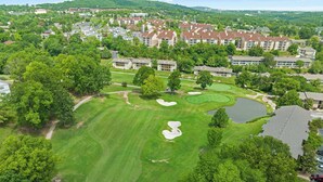 A golf course with bunkers, a pond, and residential buildings in the background. - Overlook Paradise Scenic Stay (Branson)