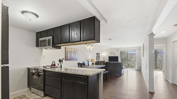 A modern kitchen with dark cabinetry, a central island, and a built-in microwave. - Overlook Paradise Scenic Stay (Branson)