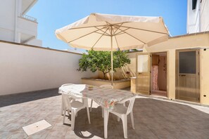 An outdoor patio with a table and chairs, a beige umbrella, and a potted plant. - Holiday Home 'Casa '719'' with Private Terrace and Private Garden (Lido Marini)