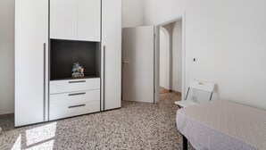 A bedroom with a bed, a wardrobe, and a door leading to another room.