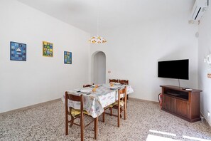 A dining area with a table set for four, a television, and artwork on the walls.