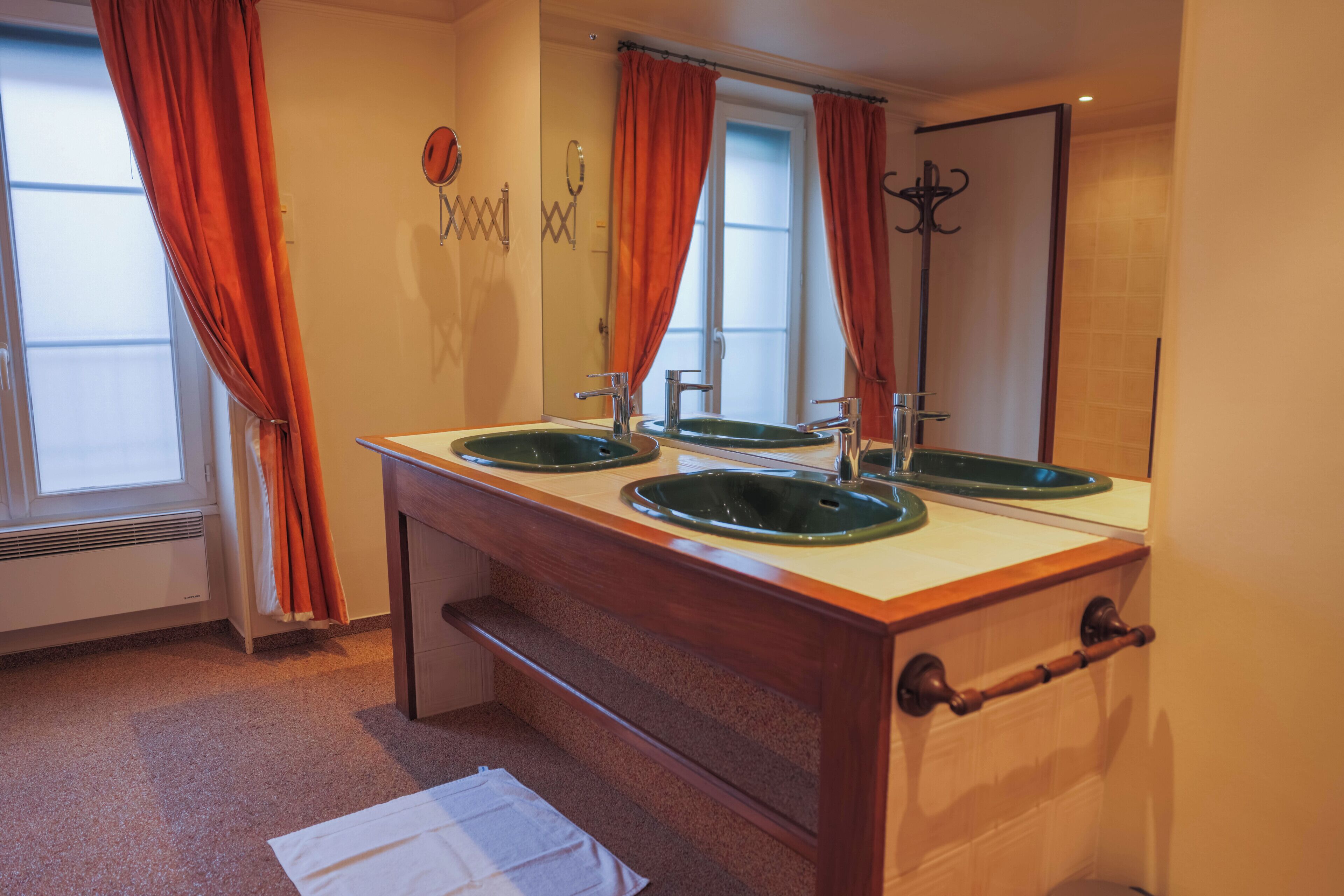 A bathroom with two sinks, a mirror, and a window with curtains.