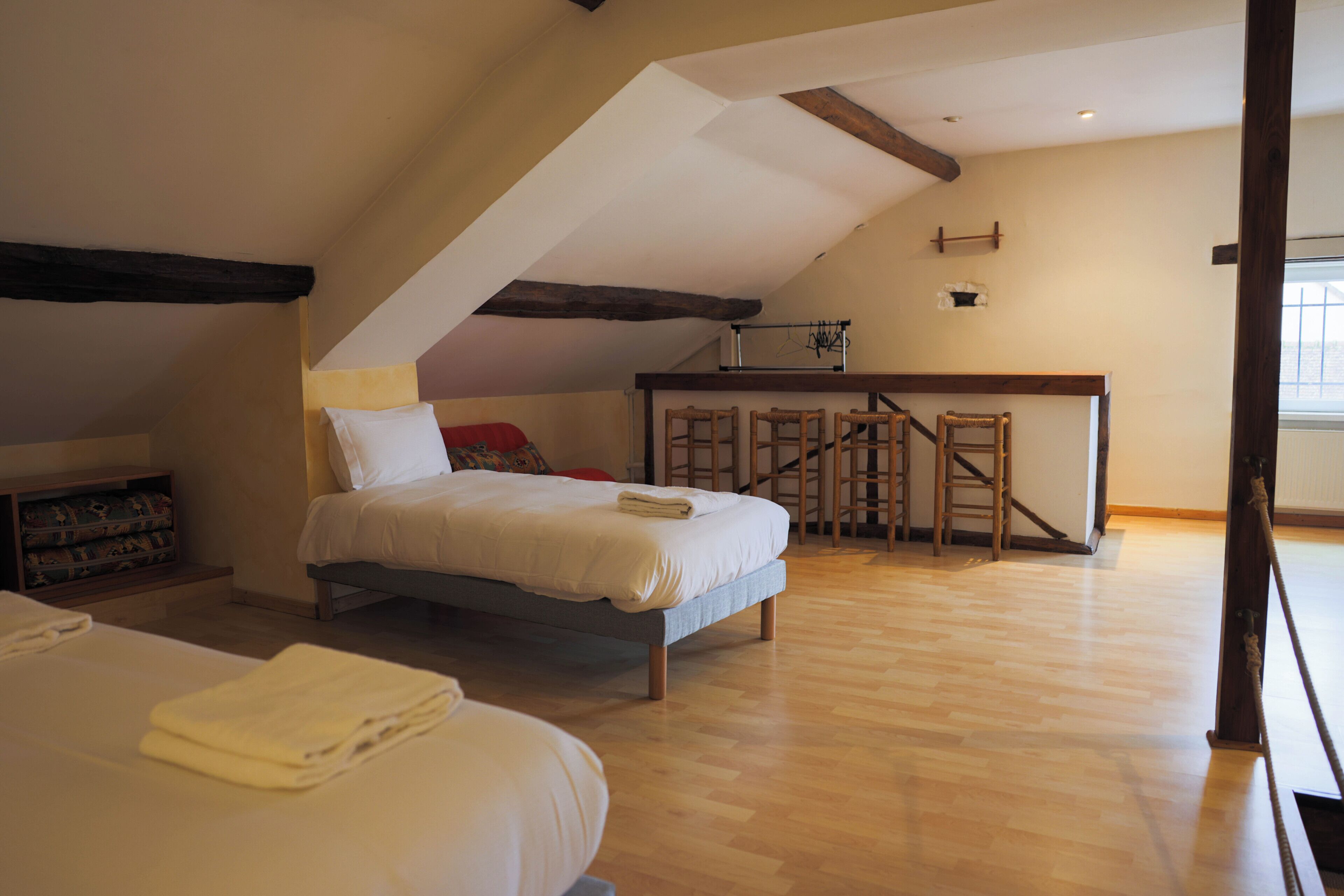 Ein Schlafzimmer mit Schlafgalerie, Holzbalken, einem Bett, einem Schreibtisch und einem Stuhl.