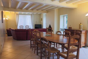 Un coin repas avec une table et des chaises en bois, un canapé et un téléviseur dans le salon.