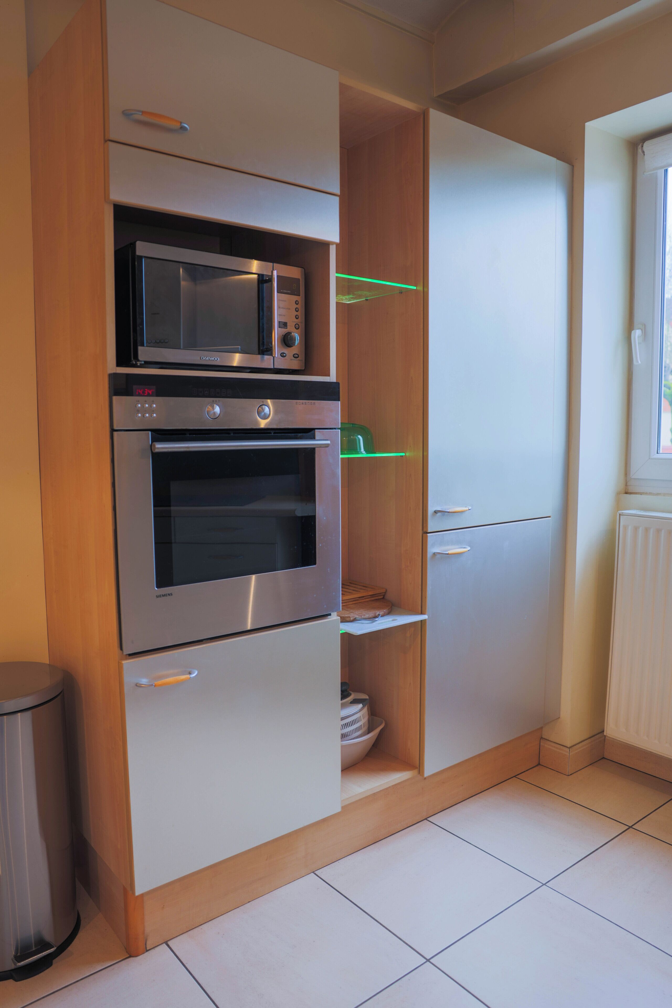 A kitchen with a microwave, oven, and refrigerator.