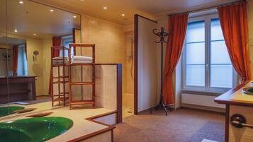 A bathroom with a bathtub, a mirror, a towel rack, and a window with curtains.
