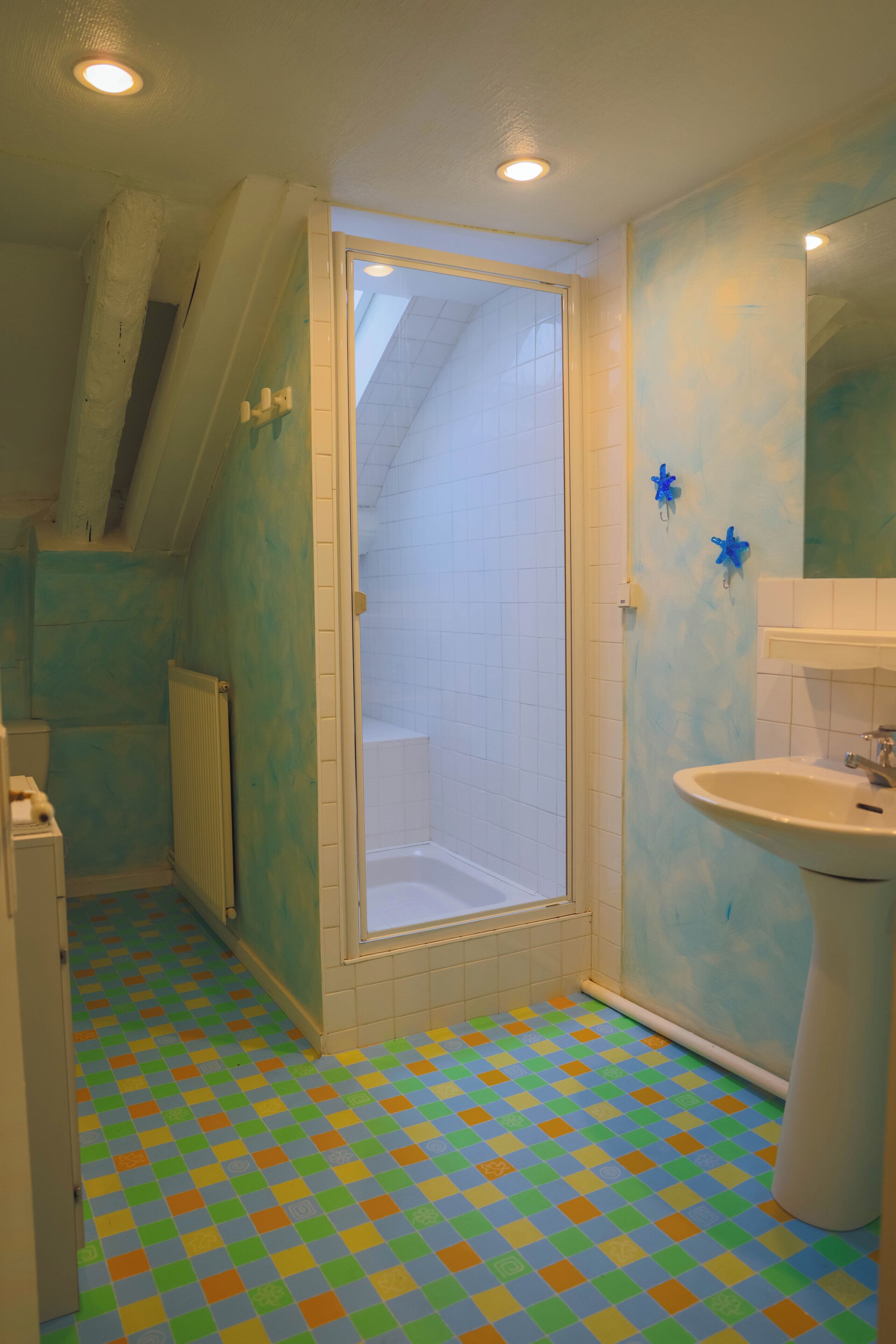 Une salle de bain avec une douche, un lavabo et un sol carrelé.