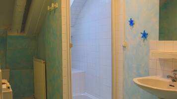 Une salle de bain avec une douche, un lavabo et un sol carrelé.