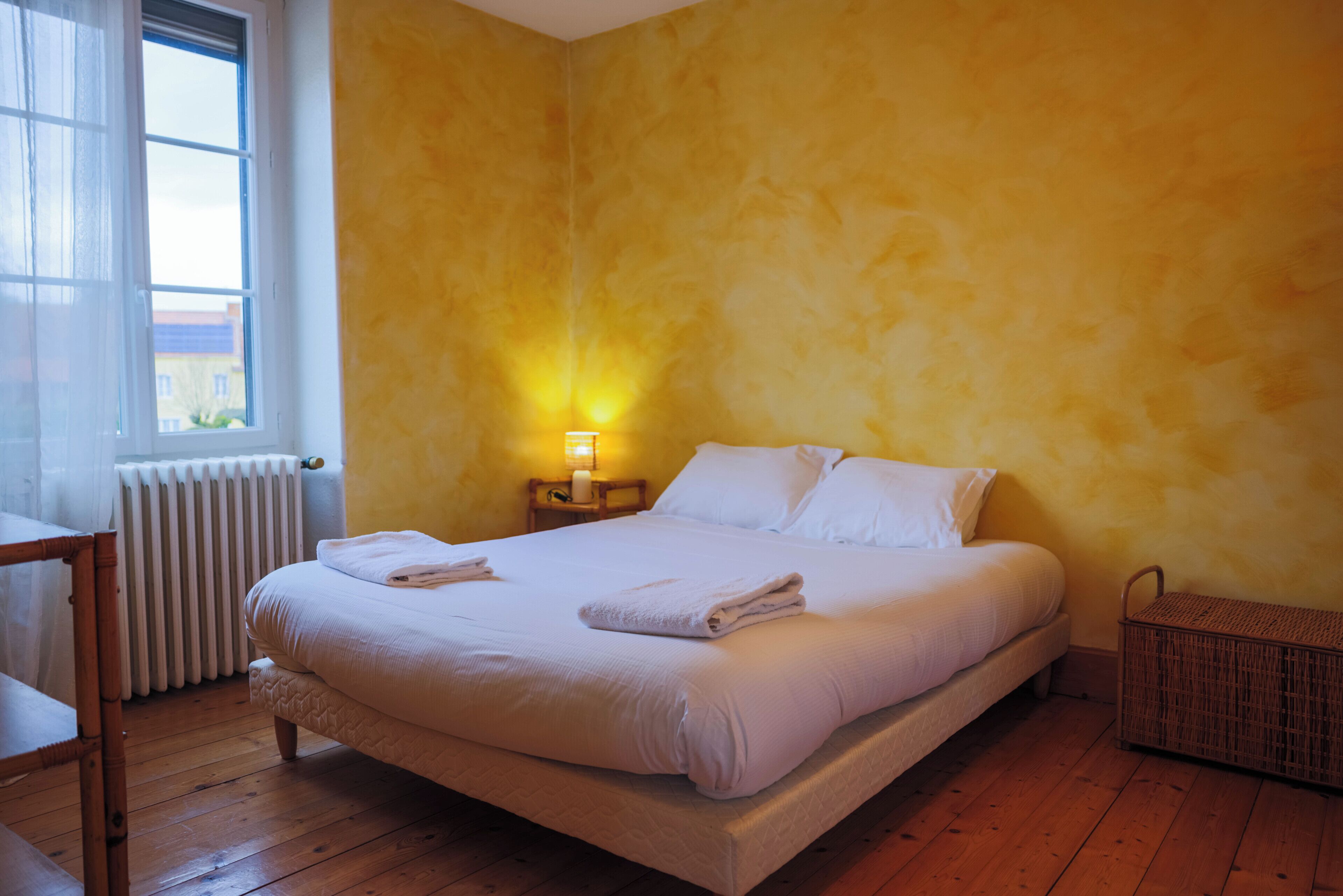 A bedroom with a bed, bedside table, lamp, and a window.