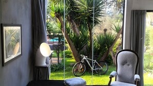 Une chambre avec un lit, une chaise, un vélo et une vue sur la verdure.