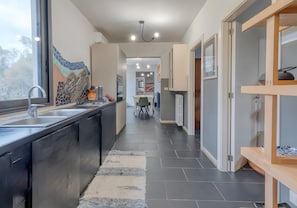 Una cocina moderna con un ventanal grande, piso de baldosas y un comedor con una silla y una mesa.