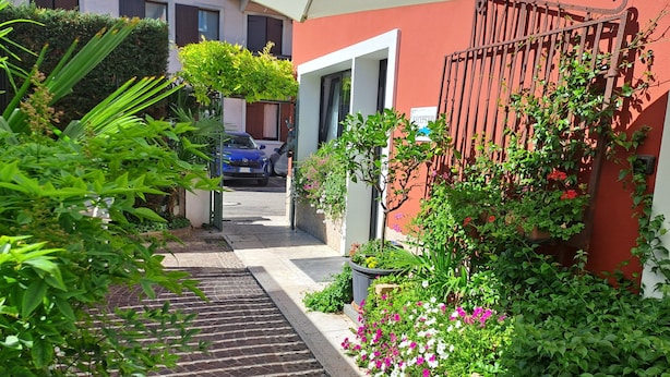 A narrow pathway leading to a building entrance, surrounded by lush greenery and potted plants. - Boutique Hotel Florivana (San Pietro in Cariano)