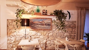 A dining area with a stone wall, a table with chairs, a hanging lamp, and a framed picture. - Boutique Hotel Florivana (San Pietro in Cariano)