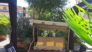 An outdoor seating area with a canopy, wicker furniture, and potted plants. - Boutique Hotel Florivana (San Pietro in Cariano)