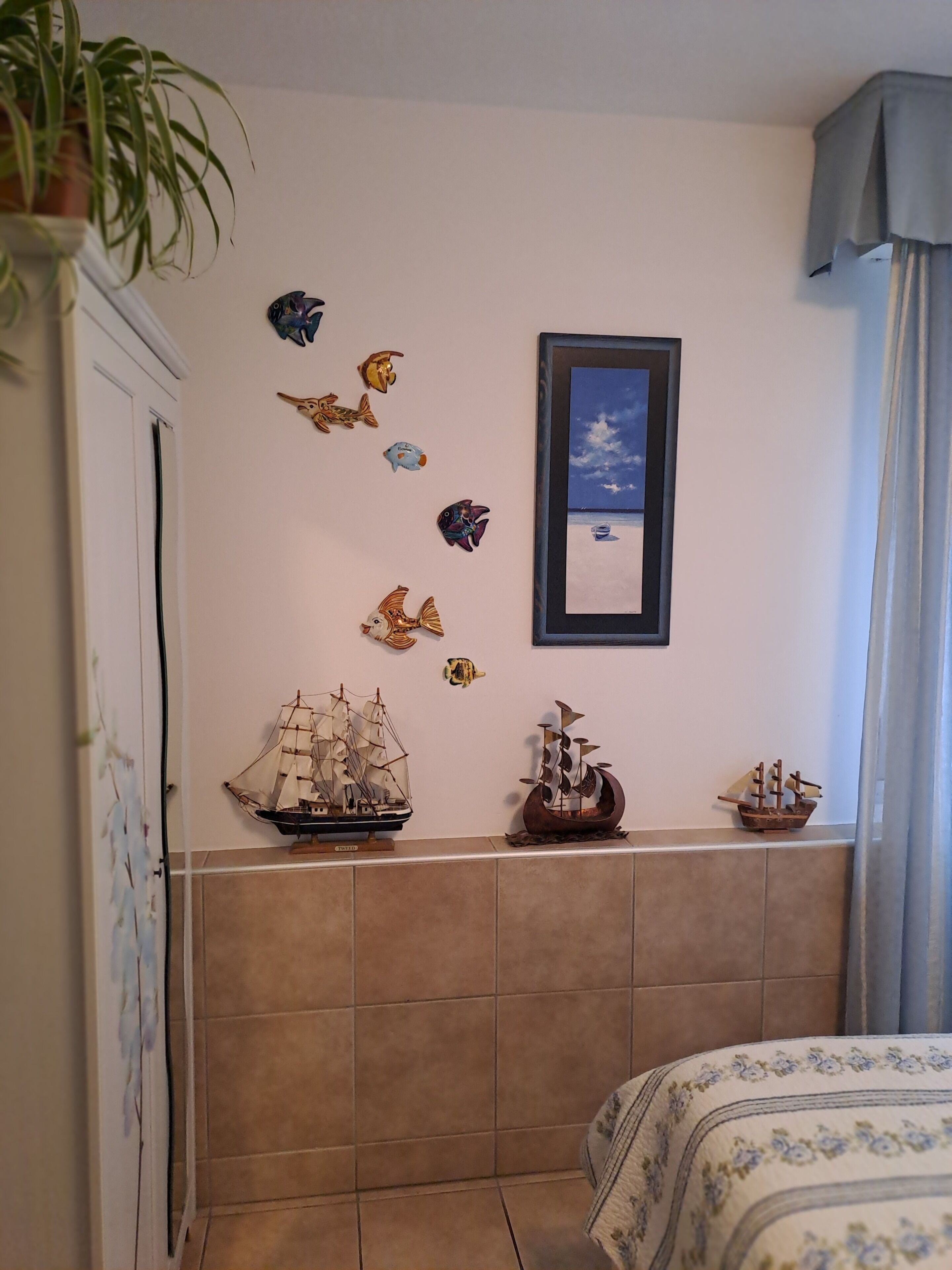 Un dormitorio con una cama, un modelo de barco en la pared y un cuadro con una playa.