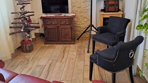 A living room with a red sofa, a television, a dartboard, and a wooden cabinet. - Boutique Hotel Florivana (San Pietro in Cariano)