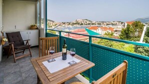 Ein Balkon mit Tisch, zwei Stühlen und einer Weinflasche.