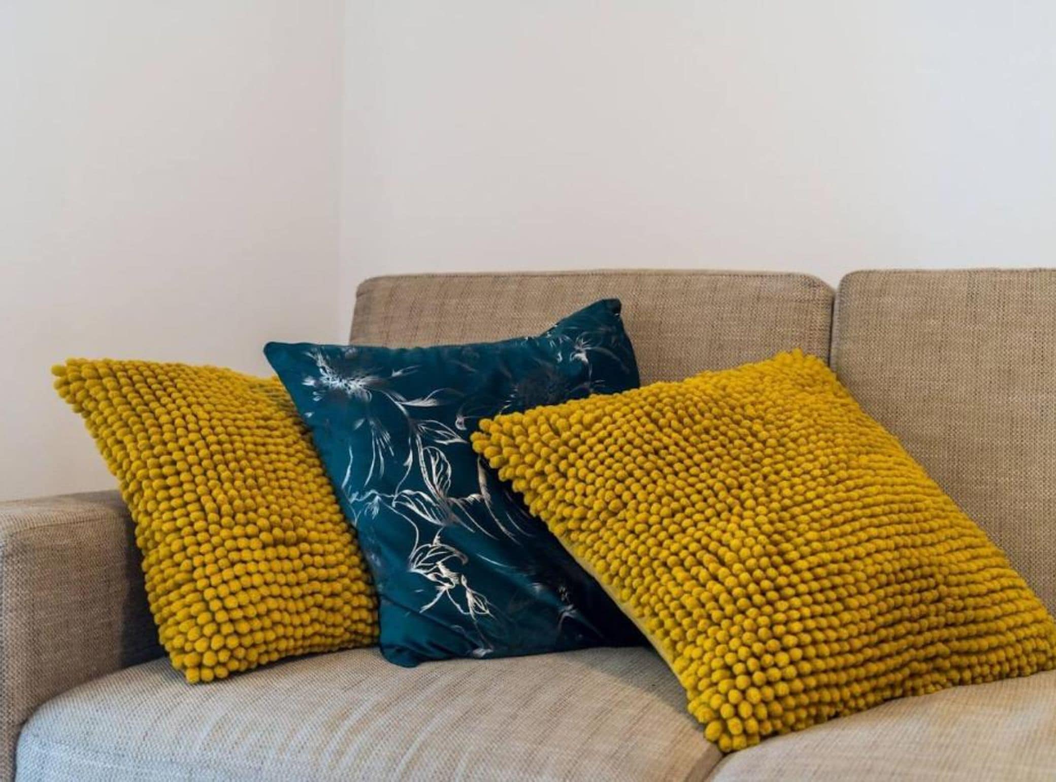 A sofa with three cushions in different textures and patterns.
