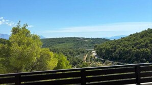 A balcony with a view of a forested hillside and a road. - Villa Coral (Novo Selo)