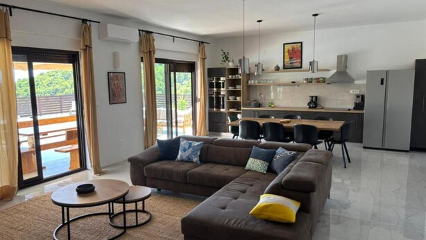 A modern living room with a sofa, coffee table, and dining area. - Villa Coral (Novo Selo)