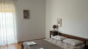 A bedroom with a bed, a nightstand, a lamp, and a painting on the wall. - Villa Coral (Novo Selo)