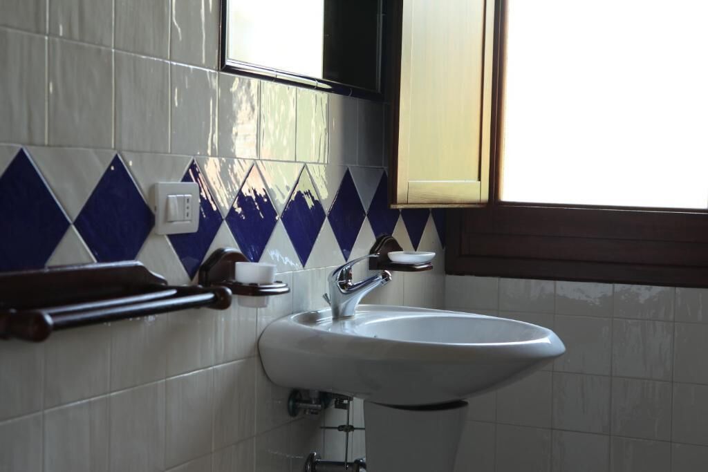 A bathroom with a white sink, a mirror, and a window.