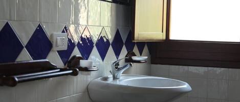 A bathroom with a white sink, a mirror, and a window.