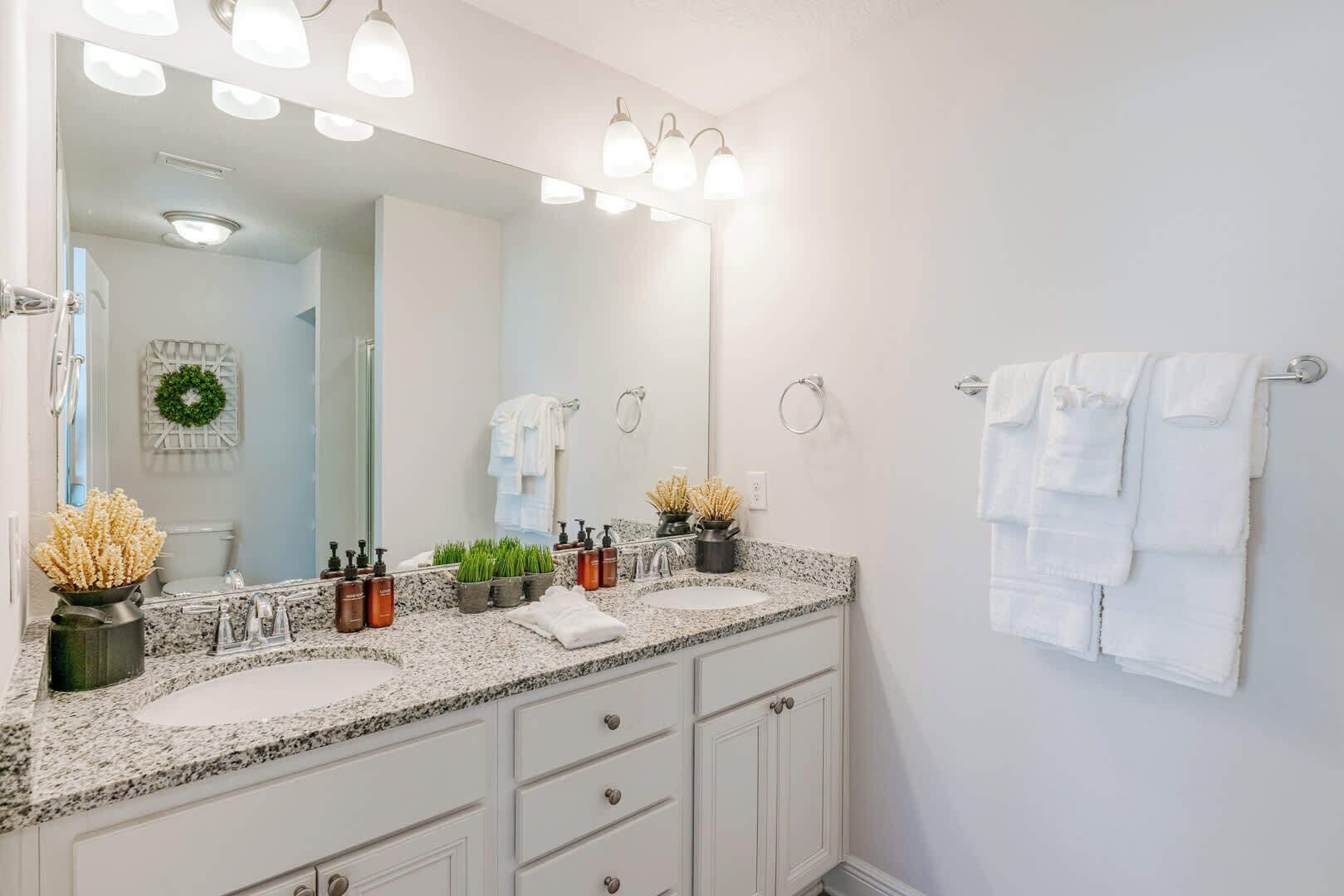 A bathroom with a double sink, a large mirror, and a towel rack.