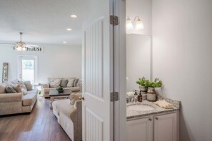 A modern interior with a living room, a kitchen with granite countertops, and a large mirror. - Shadow Lake Retreat Quick Drive to Beach, Quiet Neighborhood (Panama City Beach)