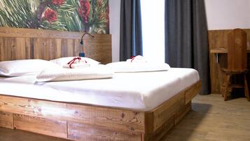 A wooden bed with white bedding, a wooden headboard, and a painting of pine cones.