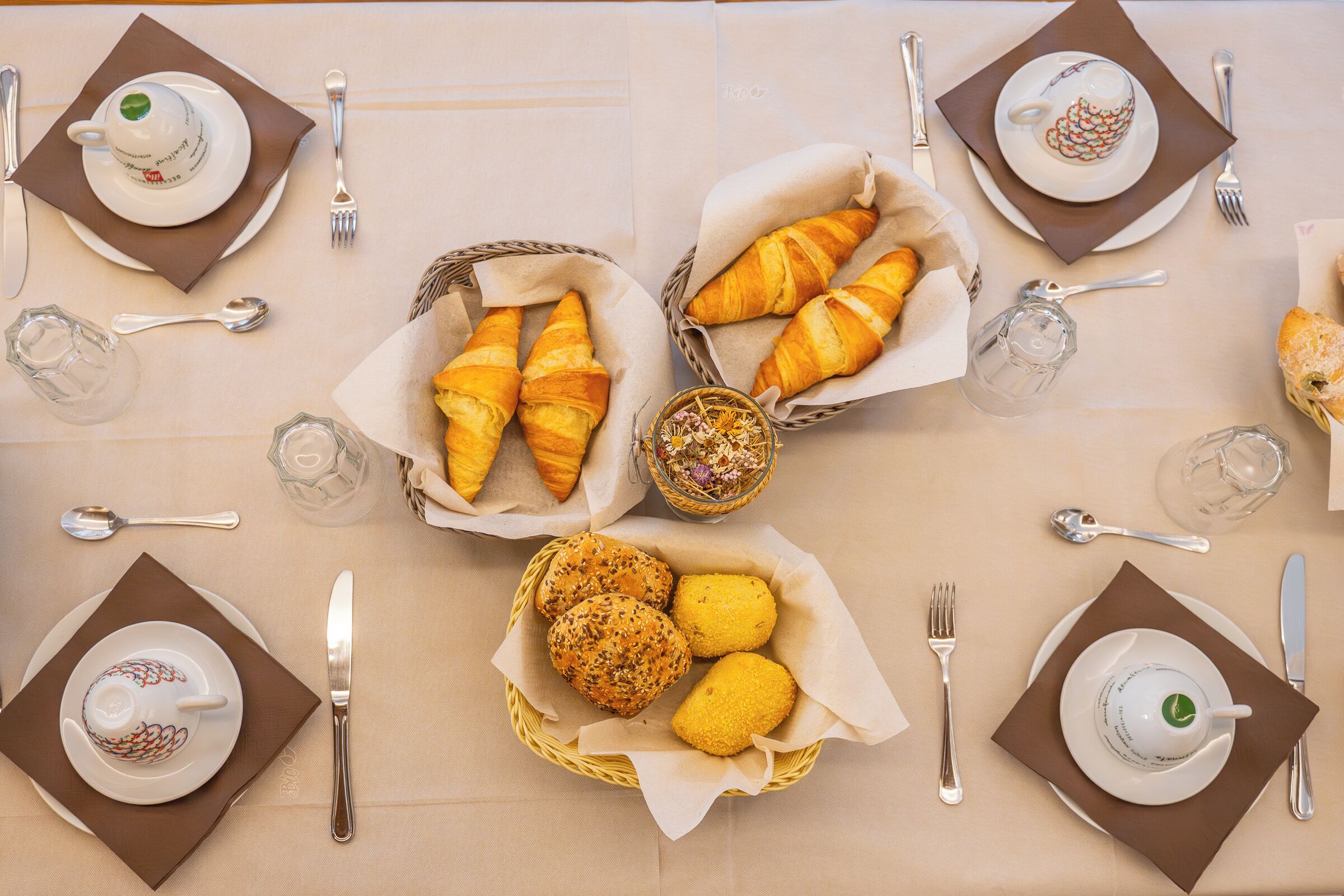 Una tavola apparecchiata per la colazione con croissant, fette di limone e tazze di caffè.