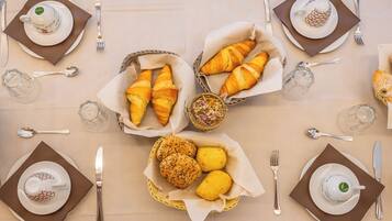 Una tavola apparecchiata per la colazione con croissant, fette di limone e tazze di caffè.