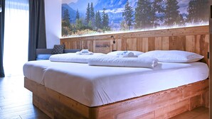 A double bed with white linens, a wooden headboard, and a large forest mural on the wall. - Mas dei Masi (Cavalese)