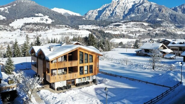 A wooden chalet with a balcony, surrounded by snow-covered mountains and a clear sky. - Mas dei Masi (Cavalese)