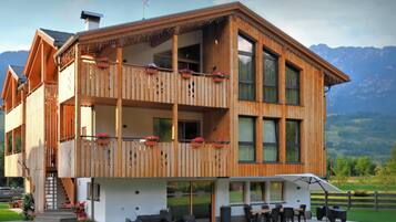 Un chalet de madera con balcones, un patio y vistas a las montañas.