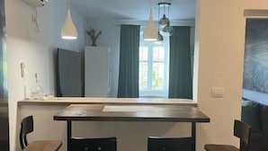 Un comedor con mesa y sillas, una ventana con cortinas e iluminación colgante.