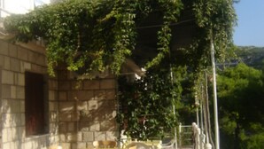 Un espace de restauration en plein air, avec des murs en pierre et des tables jaunes, entouré de verdure.