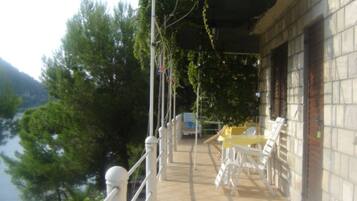Una terraza con asientos al aire libre, vistas a árboles y un edificio de paredes de piedra.