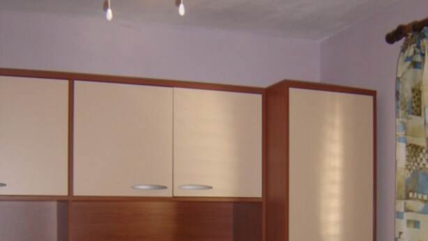 A room with a wooden cabinet with multiple compartments and a curtain with a geometric pattern. - Josip Blue Horizon Apartments (Ston)