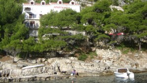 A coastal building with 'APARTMANI' signage, surrounded by greenery and rocky terrain. - Josip Blue Horizon Apartments (Ston)