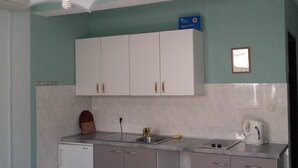 A kitchen with white cabinets, a sink, a stove, and a coffee maker. - Josip Blue Horizon Apartments (Ston)
